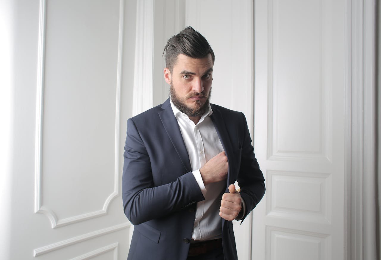 A confident businessman adjusting his suit jacket indoors, exuding style and success.